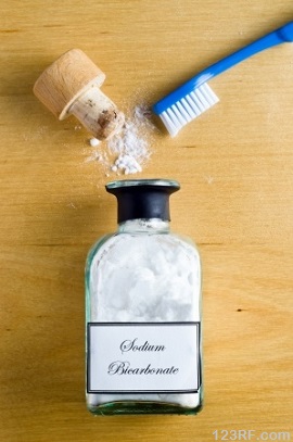 Sodium Bicarbonate bottle and toothbrush on wood background